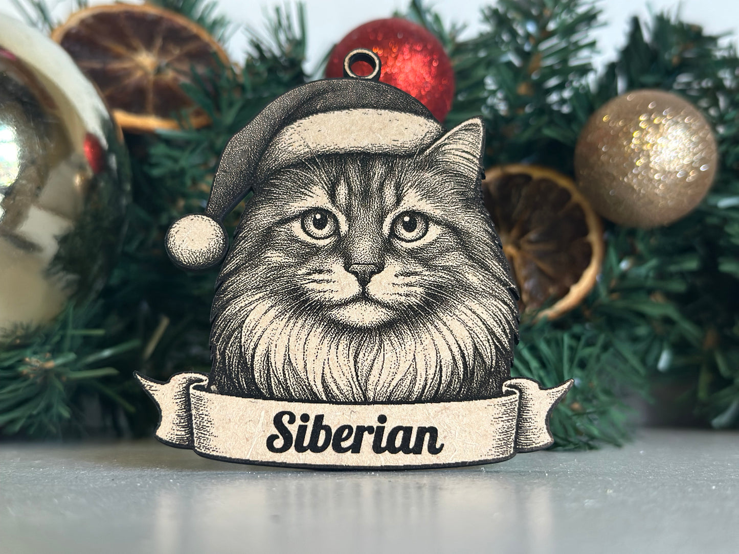 Decorative Christmas ornament with a siberian cat wearing a Santa hat on a tree.