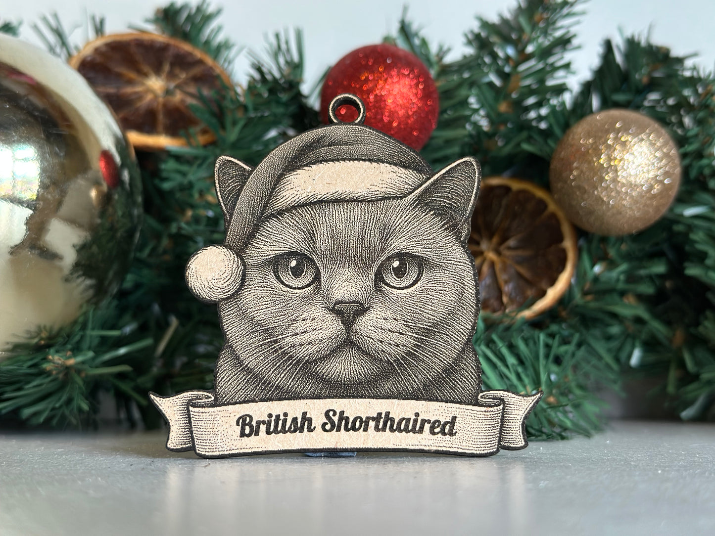 Decorative Christmas ornament with a british shorthaired cat design and festive elements on a green background.