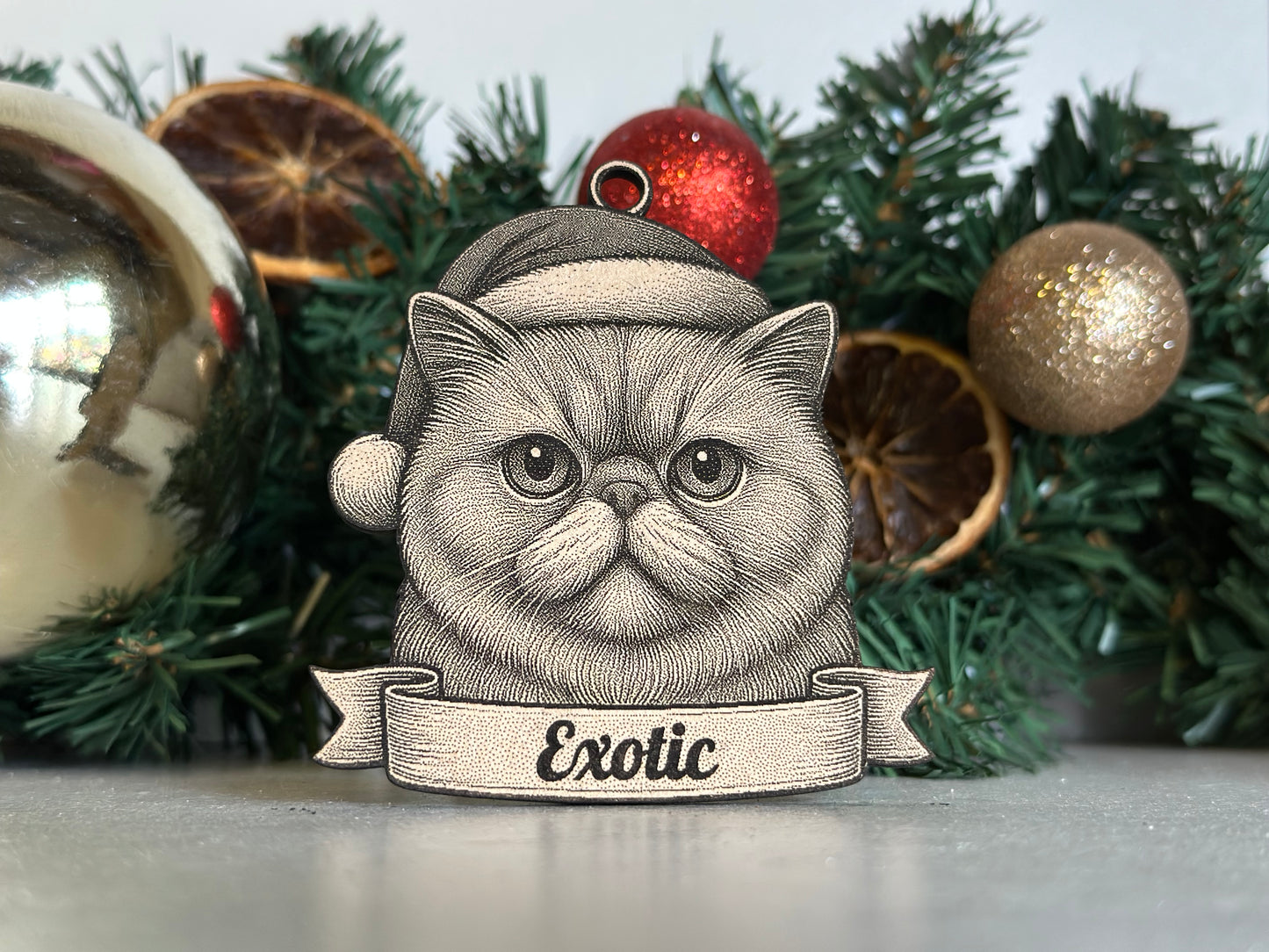 Decorative ornament of an exotic cat with a Christmas hat in front of festive decorations.