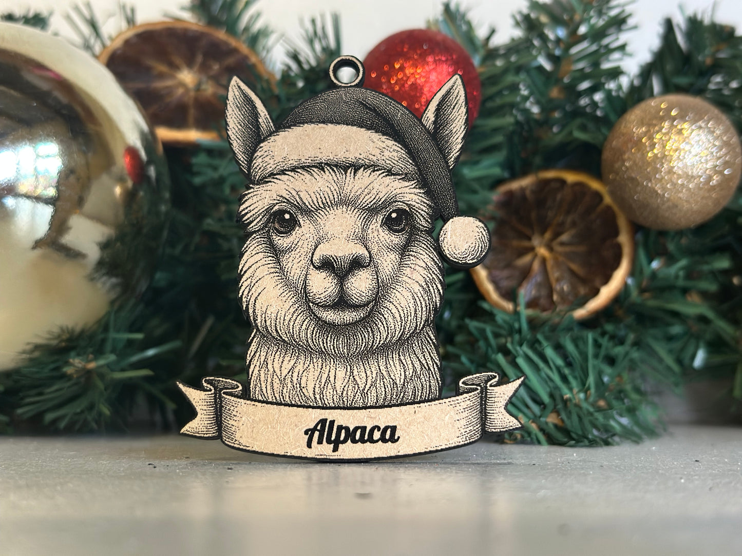 Decorative ornament of an alpaca wearing a Santa hat with Christmas decorations in the background.