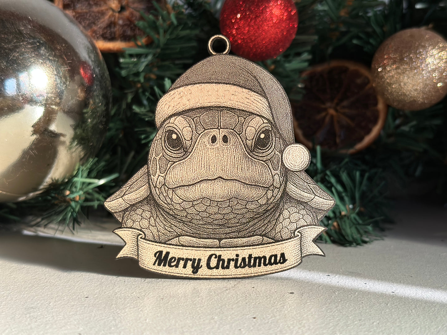 Decorative turtle ornament with a Santa hat and 'Merry Christmas' banner, surrounded by Christmas decorations.
