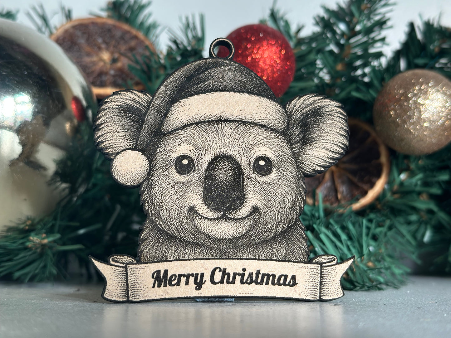 Illustration of a koala wearing a Santa hat with 'Merry Christmas' banner on a Christmas tree background.