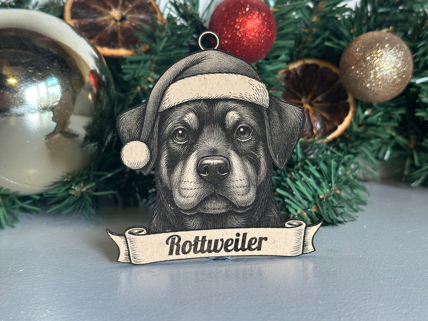 Decorative Christmas ornament with Rottweiler dog illustration on a green tree with ornaments.