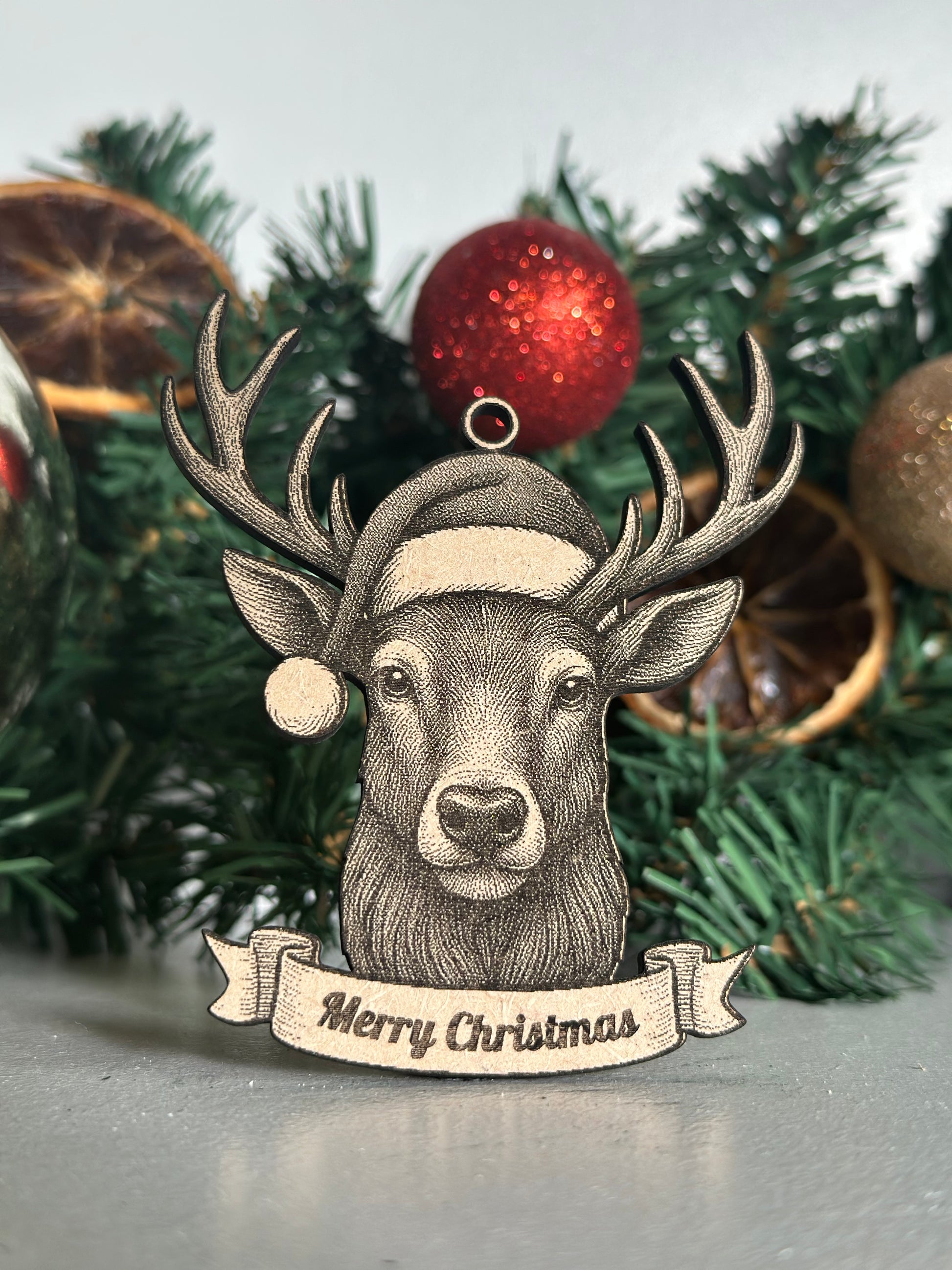 Decorative Stag ornament with 'Merry Christmas' banner on a Christmas tree.