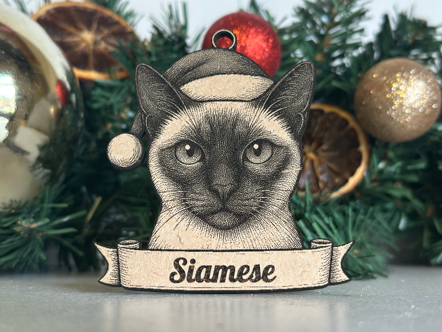 Decorative siamese cat ornament with a banner on a Christmas tree.