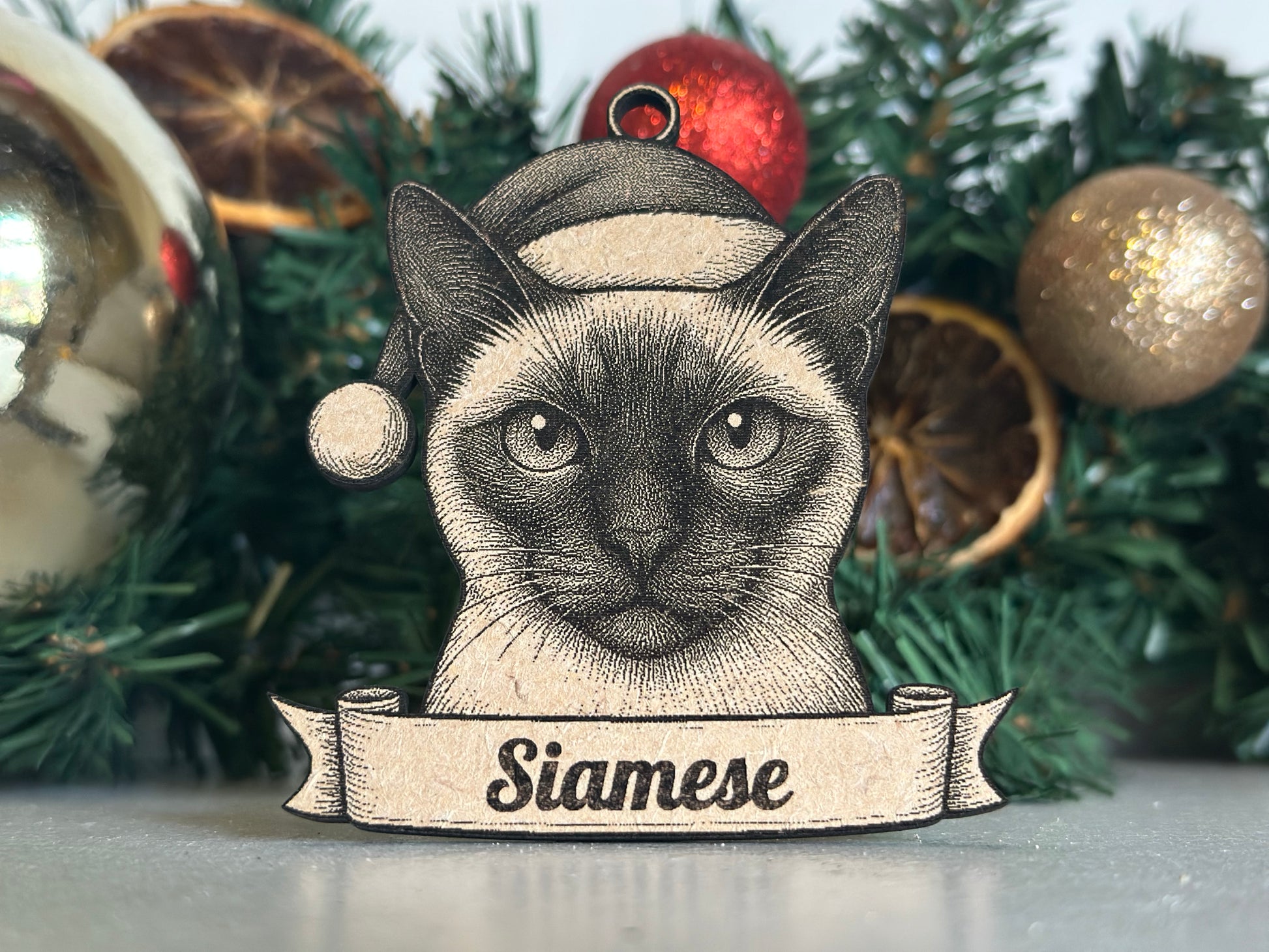 Decorative siamese cat ornament with a banner on a Christmas tree.