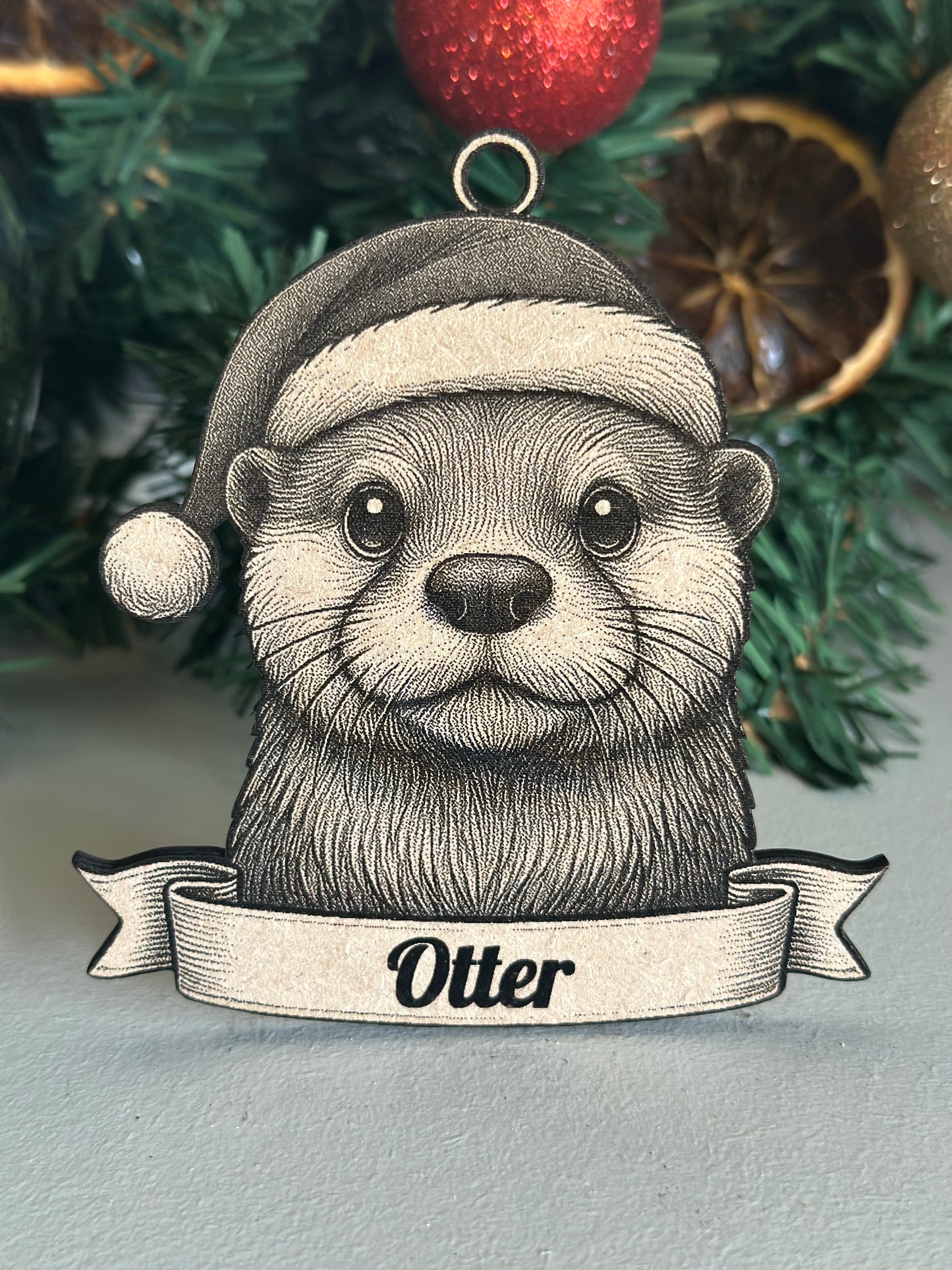 Ornament with an otter design and 'Otter' text on a Christmas tree background