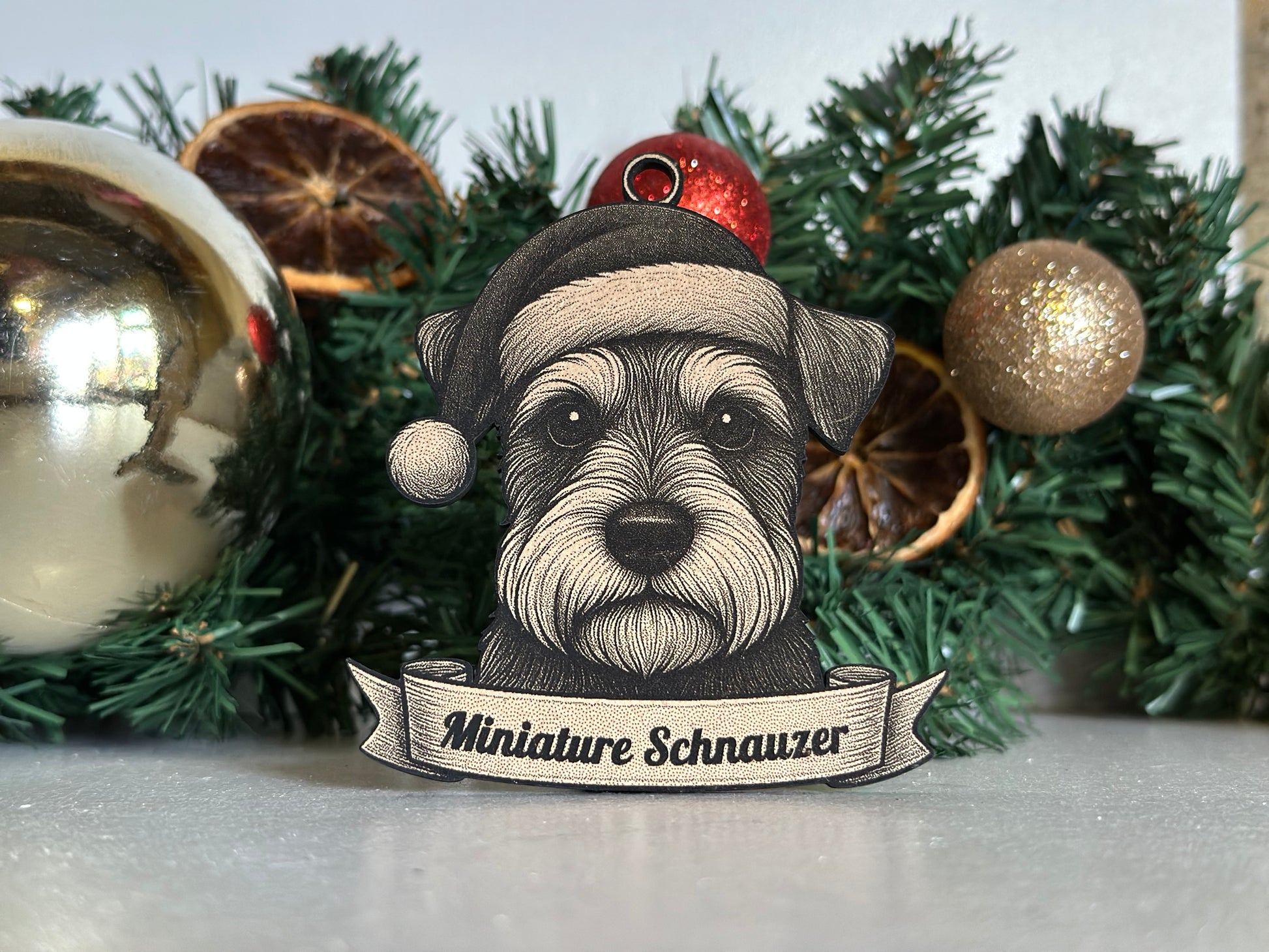 Decorative ornament with a miniature schnauzer dog illustration on a Christmas tree.