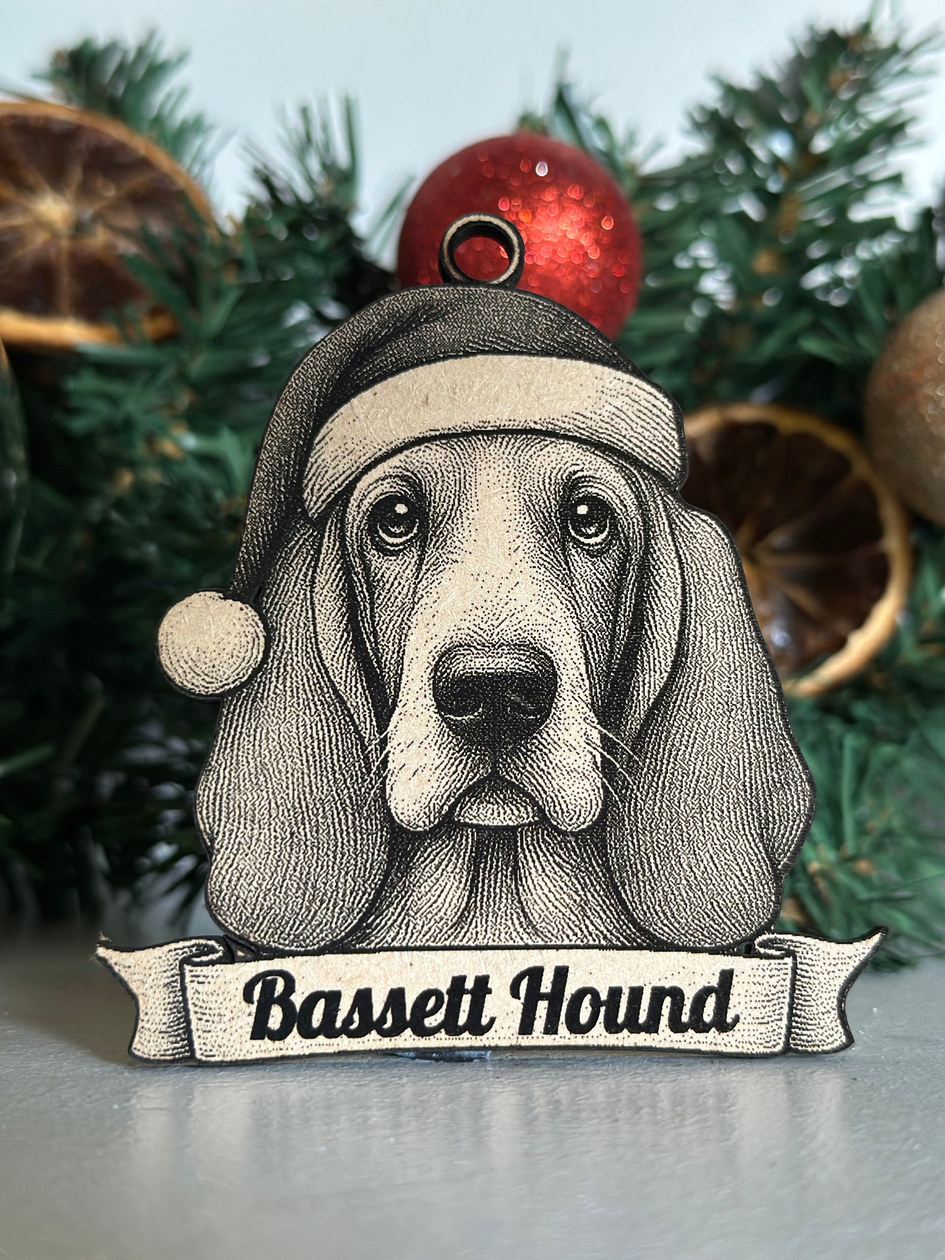 Decorative ornament of a Basset Hound with a sign on a Christmas tree.