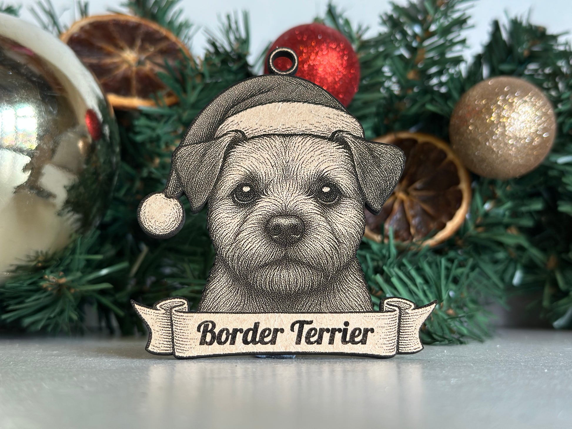 Decorative Christmas ornament with a border terrier design on a tree.