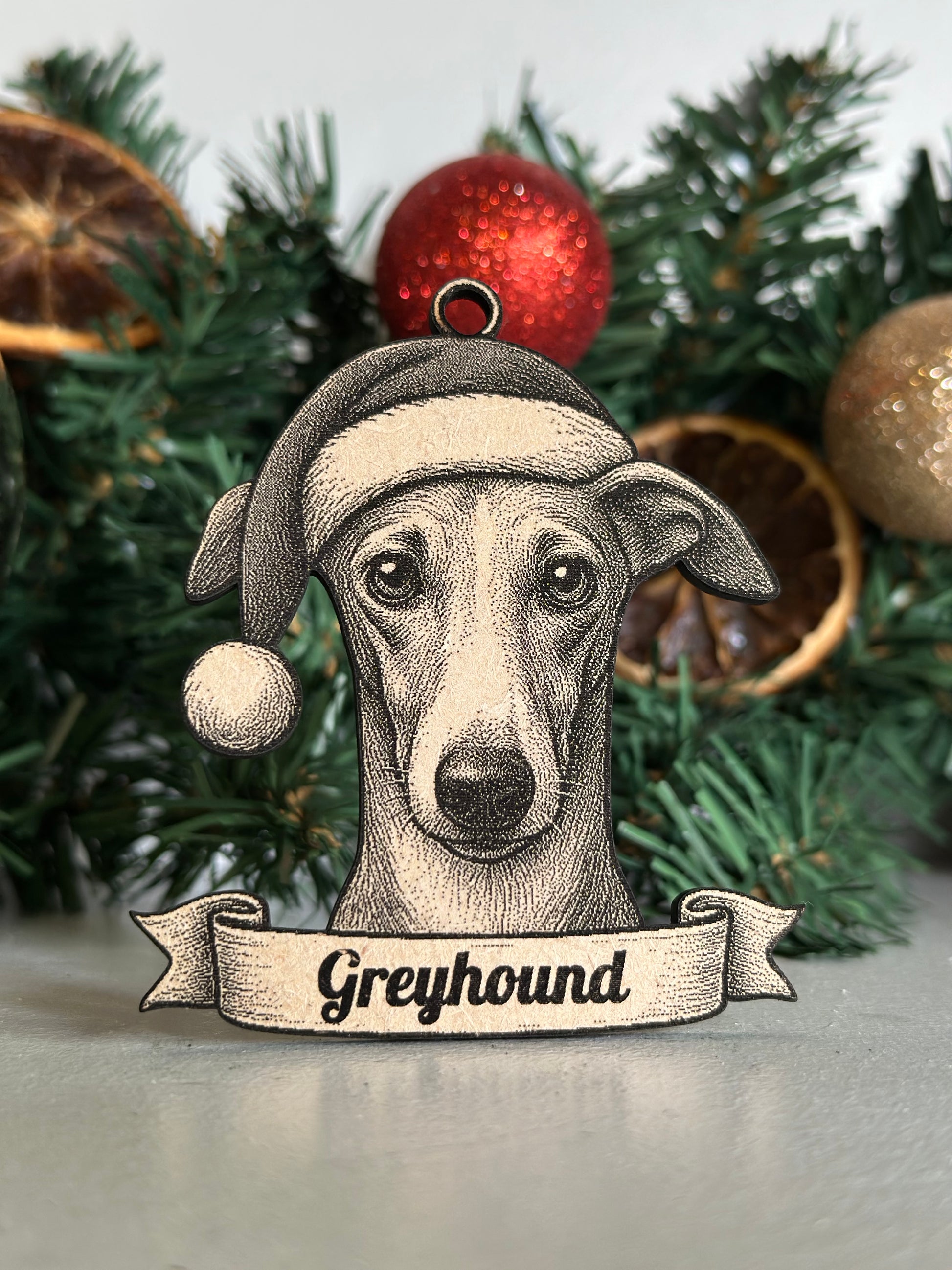 Decorative Christmas ornament of a greyhound with a Santa hat on a Christmas tree.