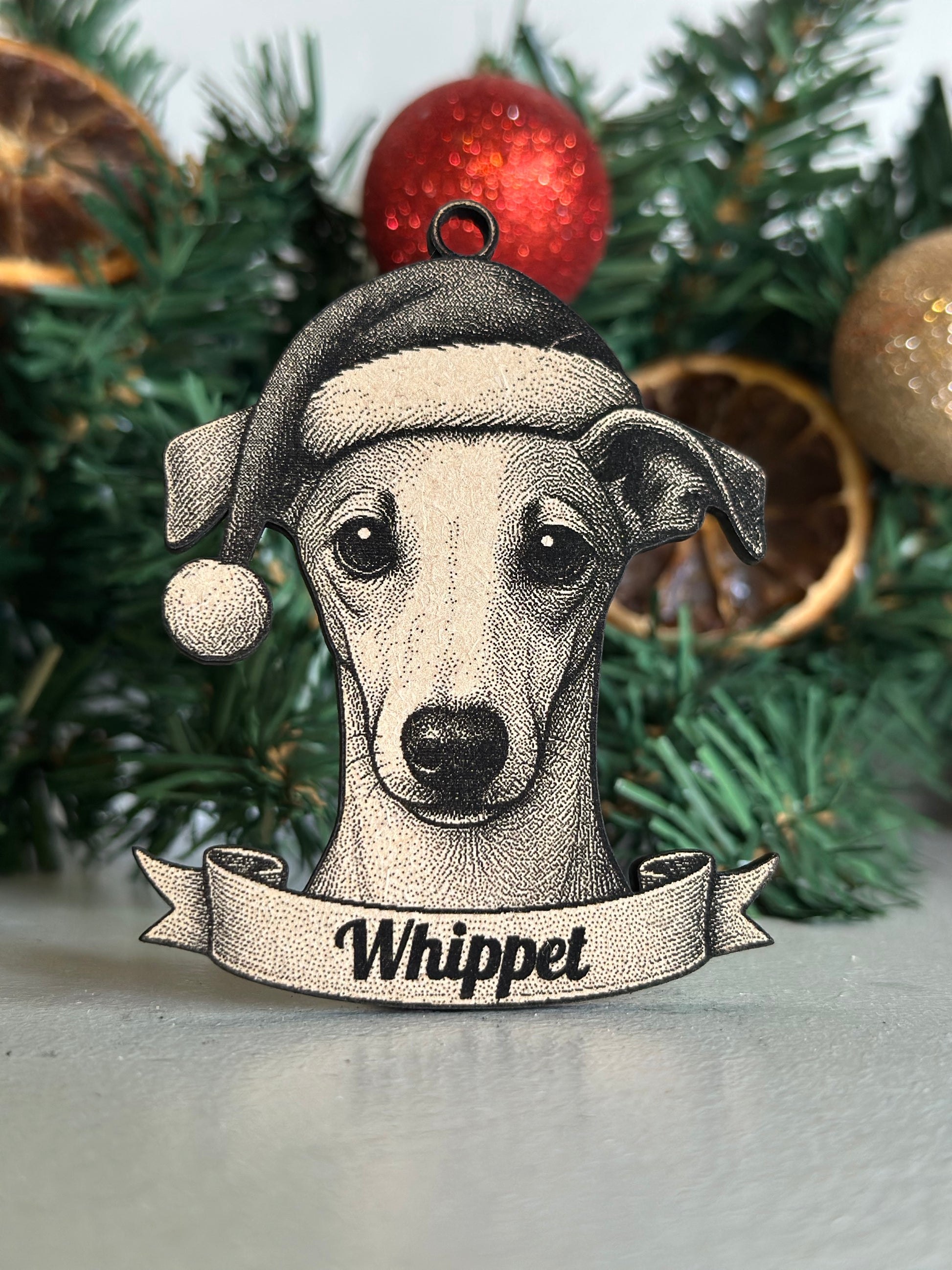 Decorative ornament of a whippet dog on a Christmas tree with ornaments.
