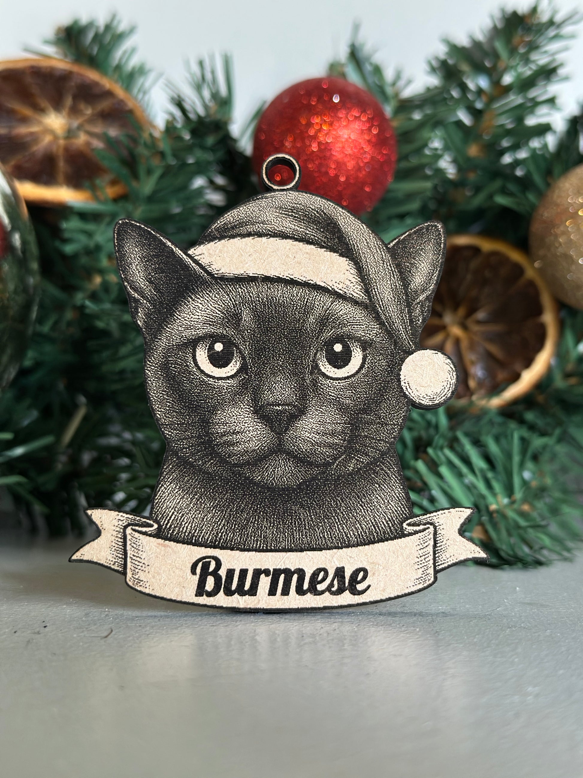 Decorative ornament of a cat with 'Burmese' text on a Christmas tree.
