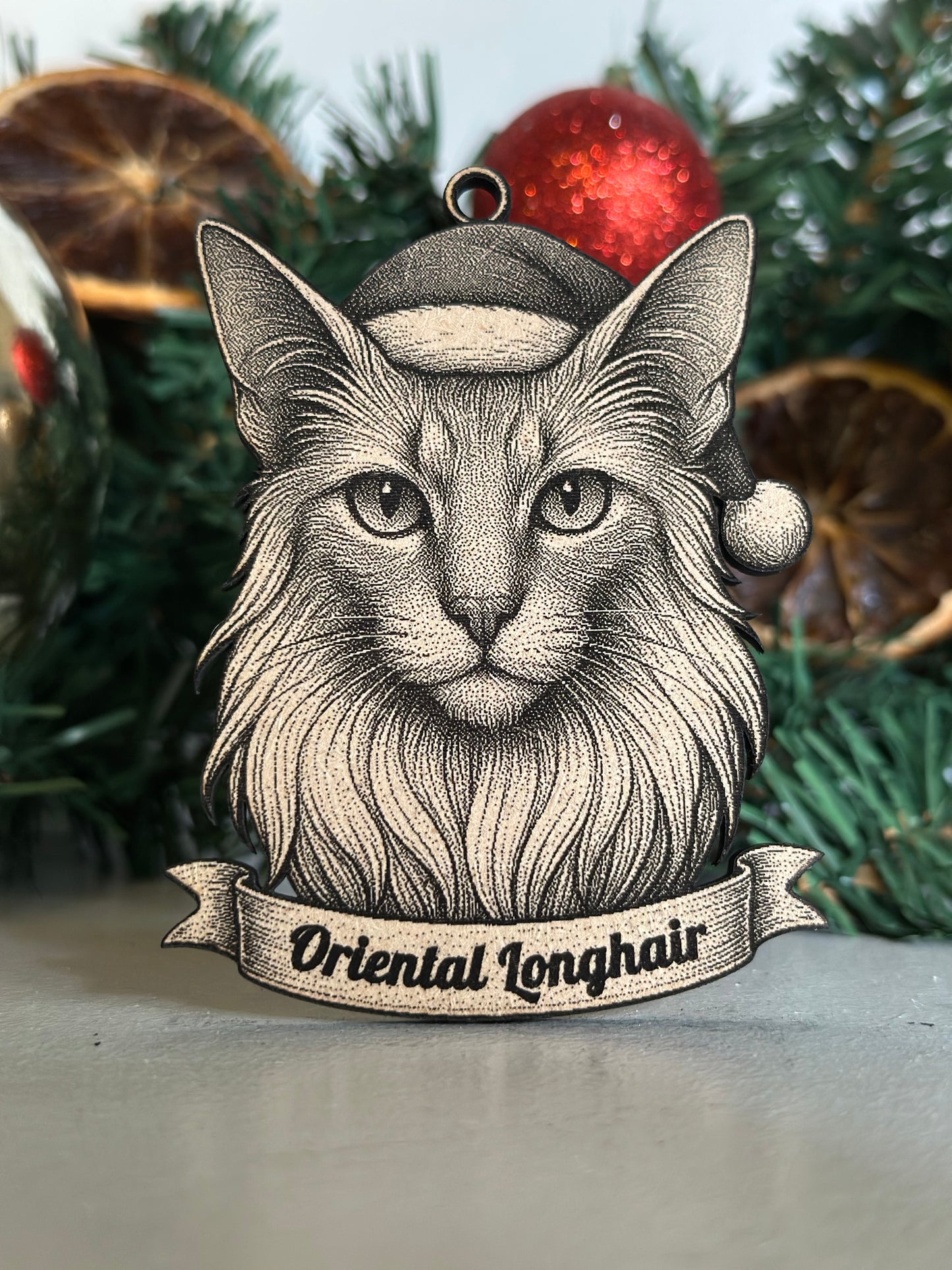 Decorative ornament with a cat's face and 'Oriental Longhair' text on a Christmas tree.