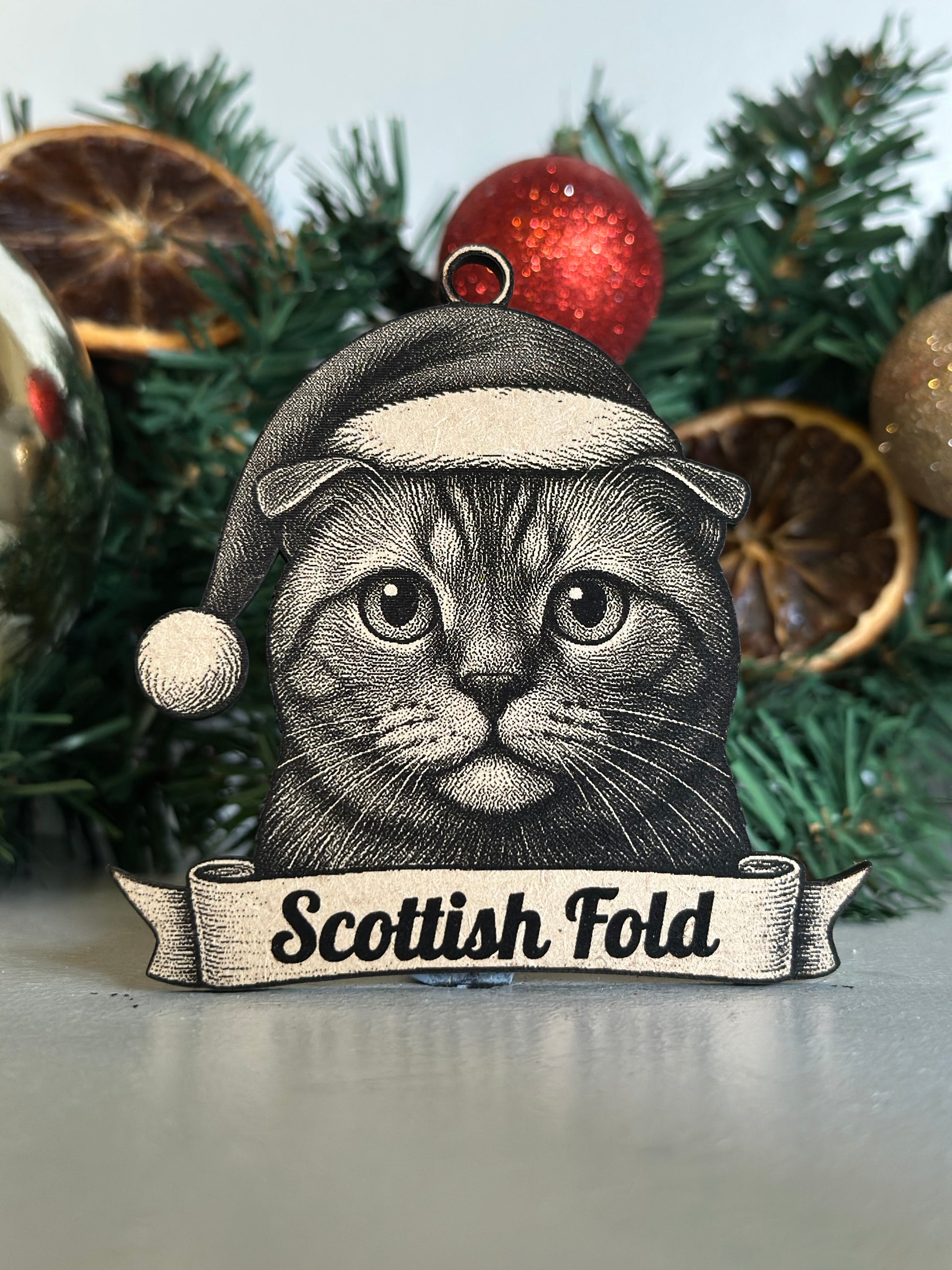 Christmas ornament with a Scottish Fold cat design on a decorated tree.