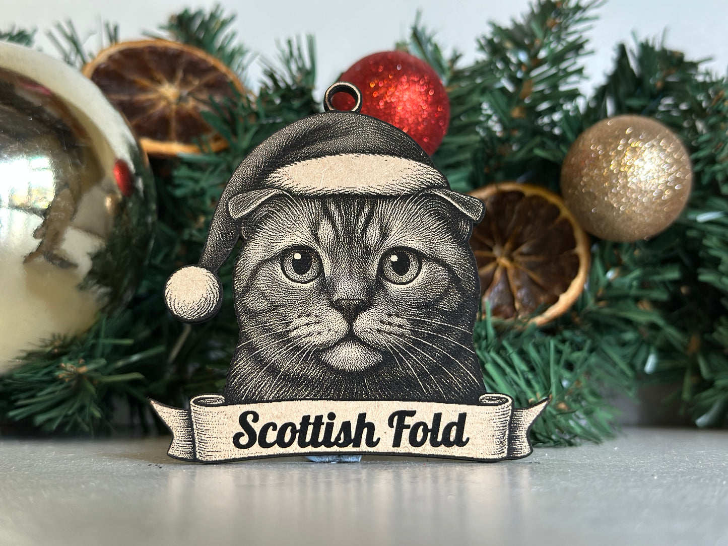 Decorative Christmas ornament with a cat illustration and 'Scottish Fold' text on a wreath background.