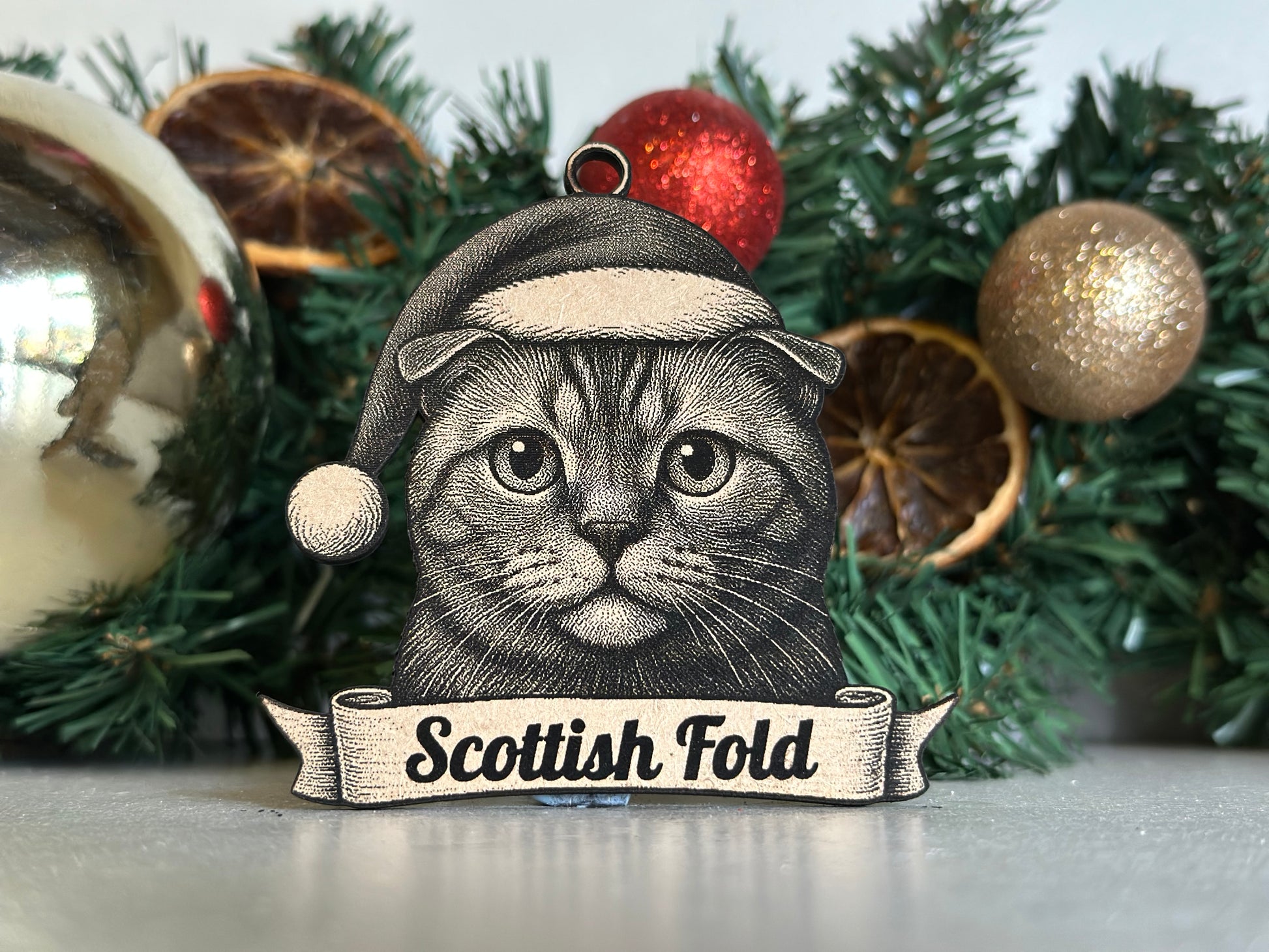 Decorative Christmas ornament with a cat illustration and 'Scottish Fold' text on a wreath background.