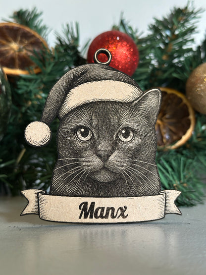 Decorative Christmas ornament with a cat design and 'Manx' banner, placed on a Christmas tree.