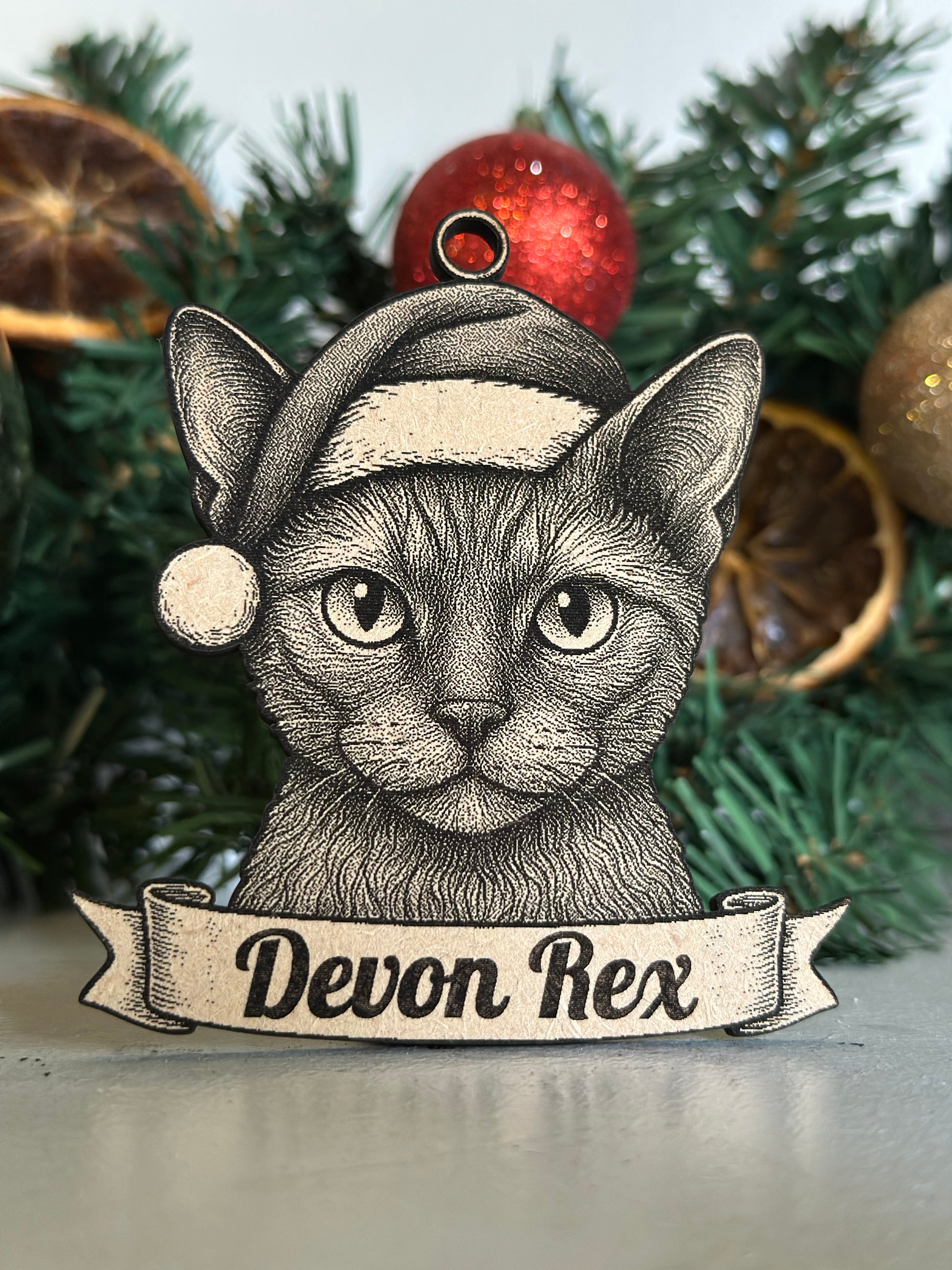 Decorative Devon Rex cat ornament on a Christmas tree with ornaments.