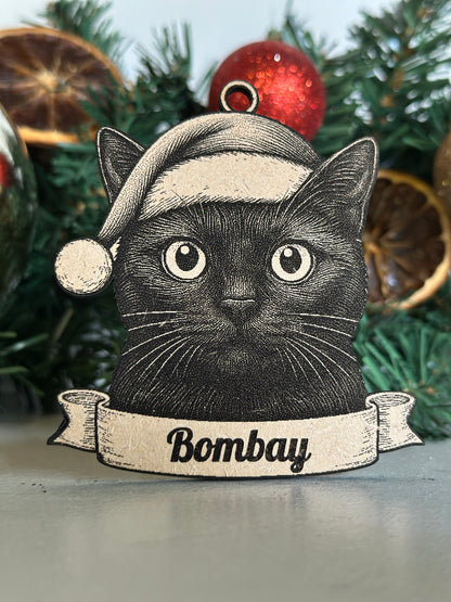 Decorative Christmas ornament with a black cat illustration and 'Bombay' text on a green wreath.
