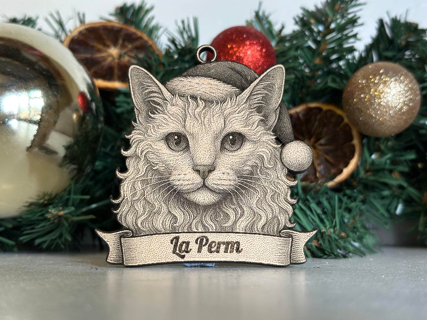 Ornament with a cat design and 'La Perm' text against a festive background with Christmas decorations.