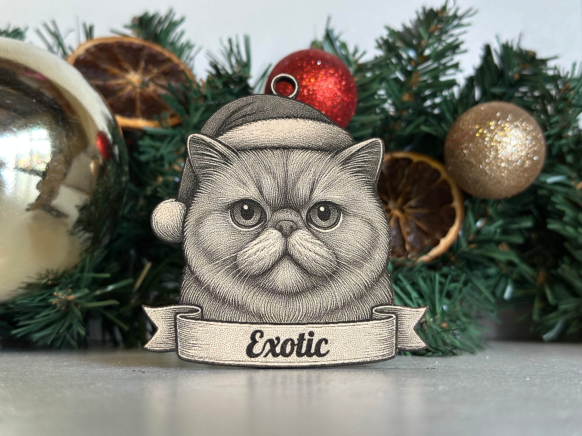 Decorative ornament of an exotic cat with a Christmas hat in front of festive decorations.