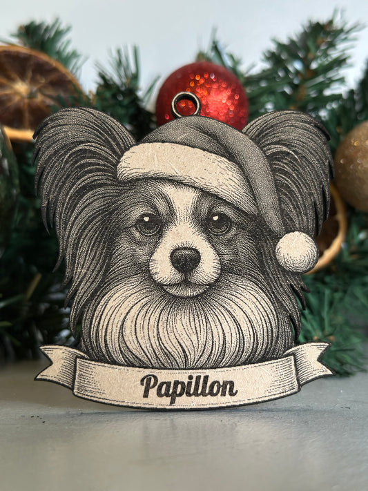 Decorative ornament with a stylized ram's head and 'Papillon' banner on a Christmas tree.