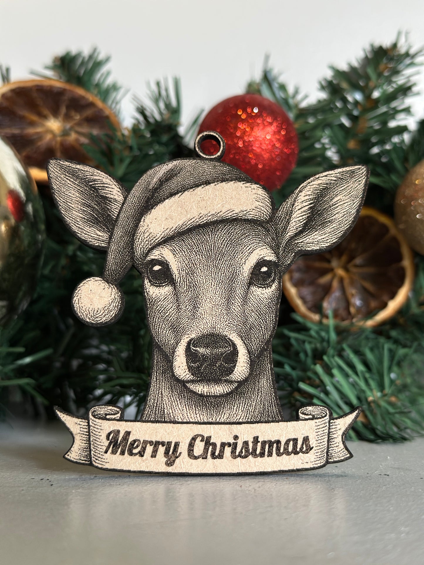 Decorative der / doe ornament with 'Merry Christmas' banner on a Christmas tree.