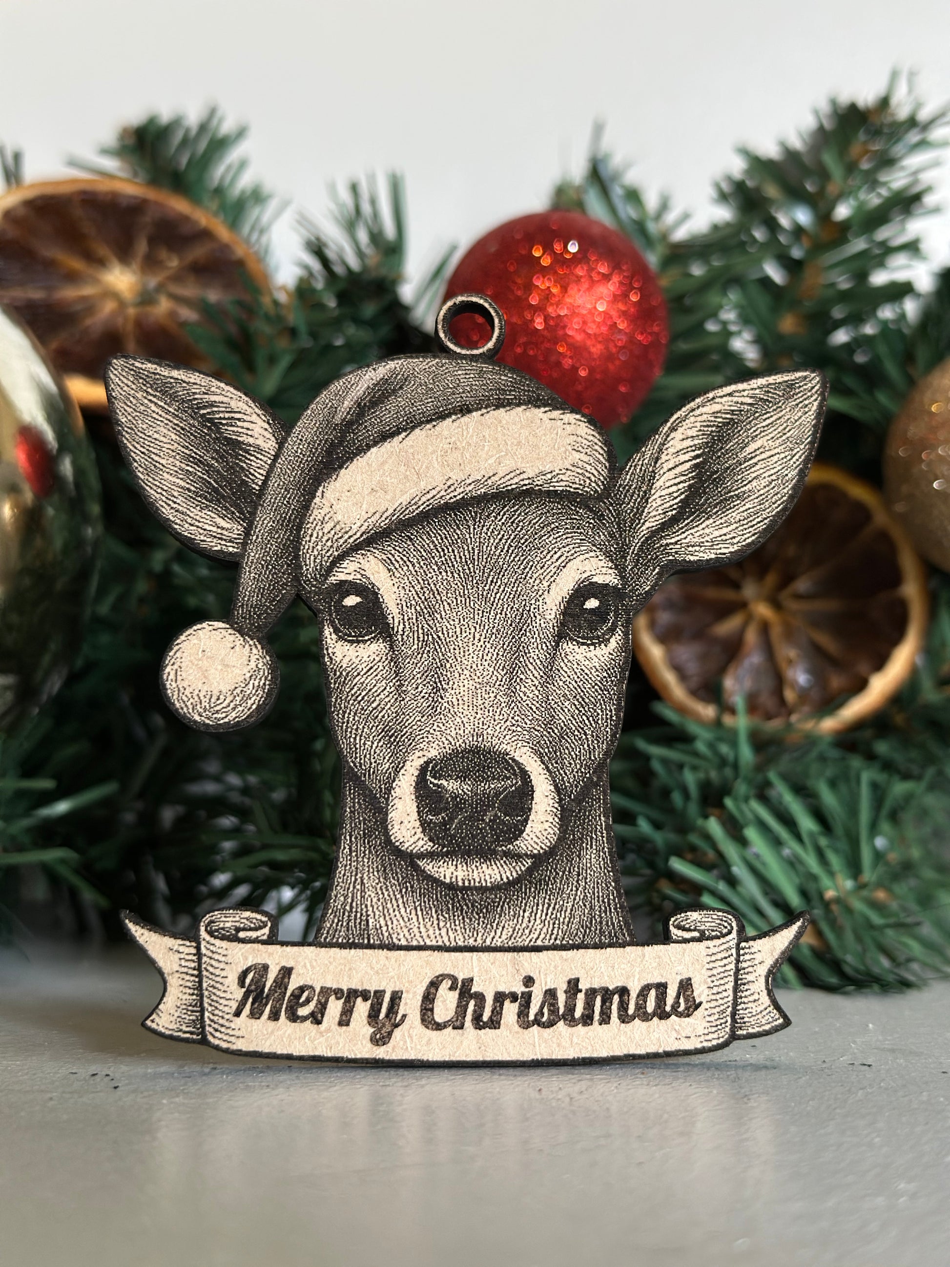 Decorative der / doe ornament with 'Merry Christmas' banner on a Christmas tree.