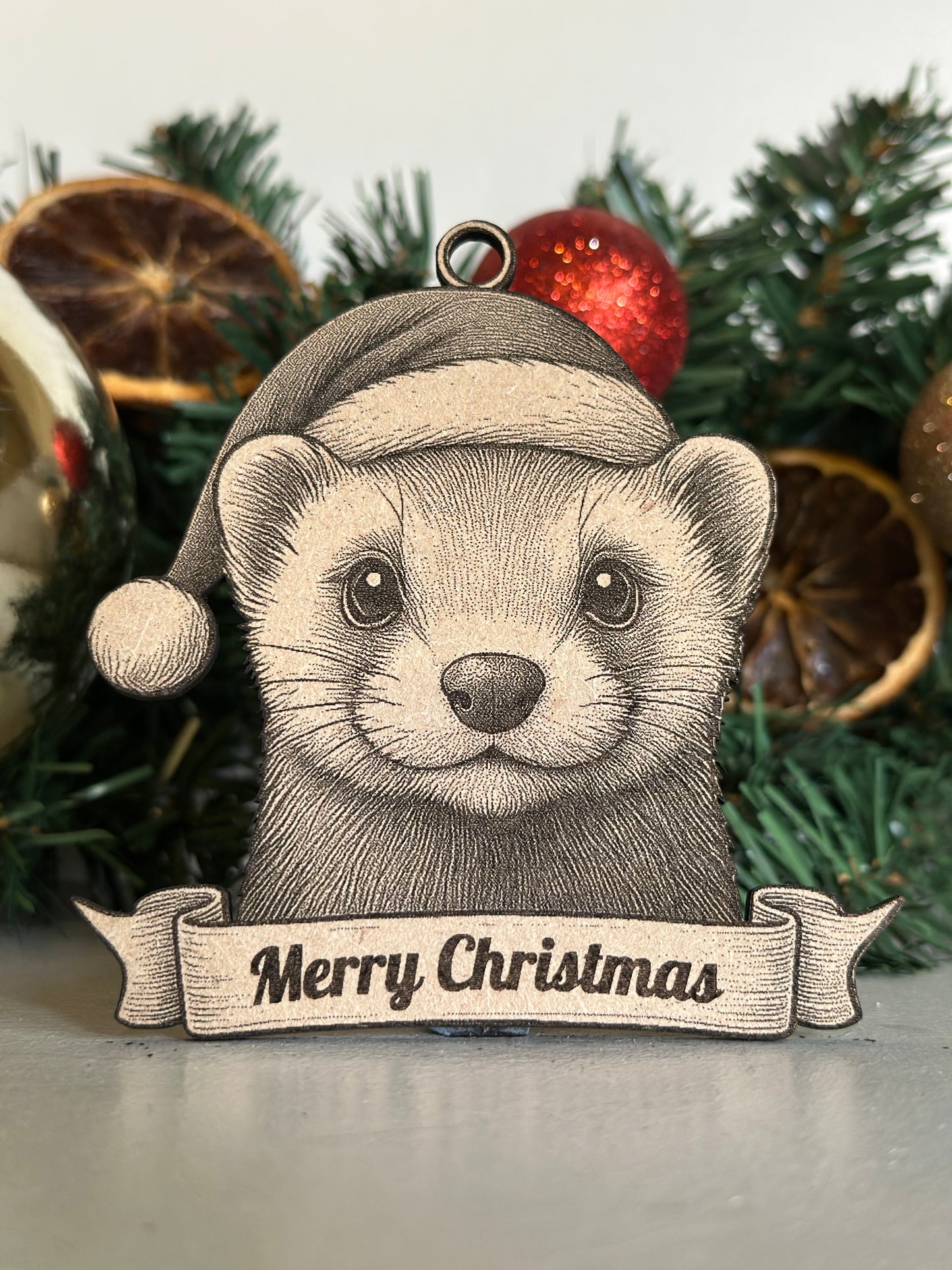 Ferrett ornament with 'Merry Christmas' banner on a decorated tree