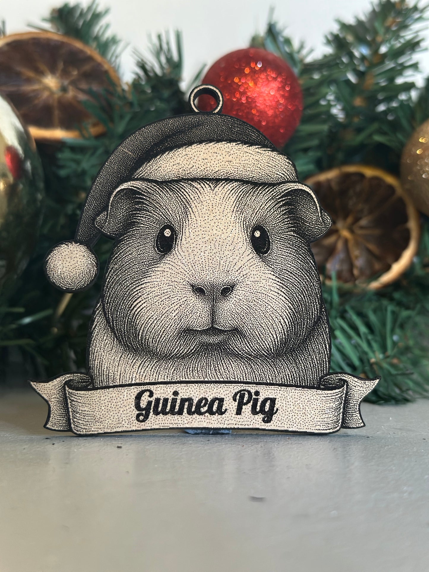 Decorative ornament of a guinea pig with a sign on a Christmas tree.