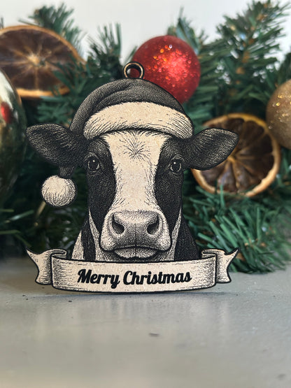 Decorative cow ornament with a Santa hat and 'Merry Christmas' banner against a festive background.
