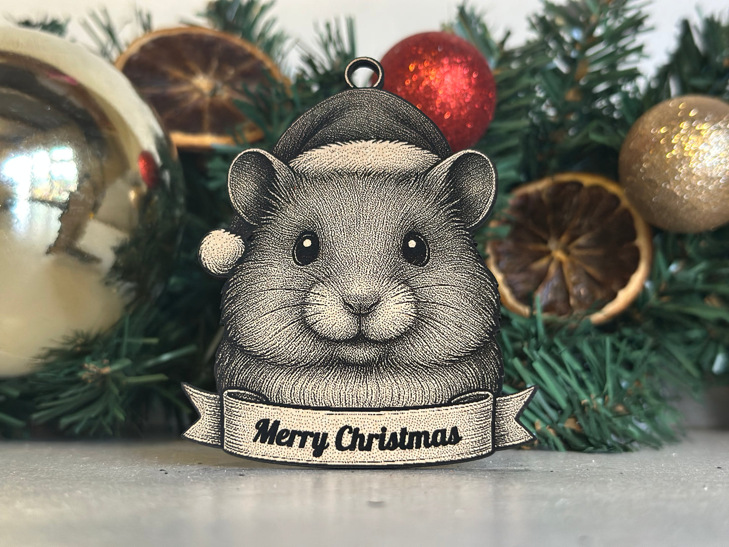 Decorative Christmas ornament with a hamster wearing a Santa hat on a tree.