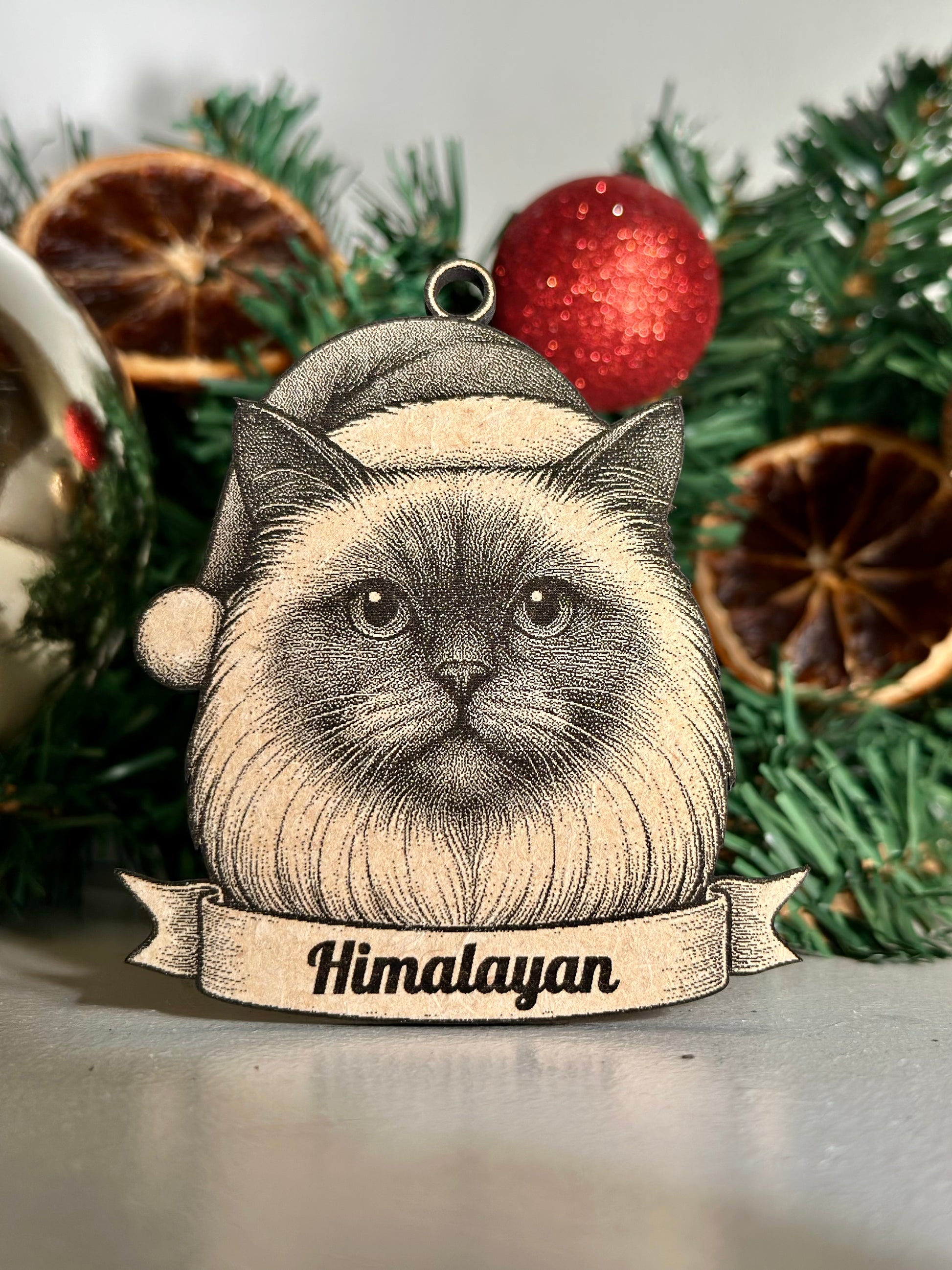 Decorative ornament with a Himalayan cat design against a Christmas-themed background.