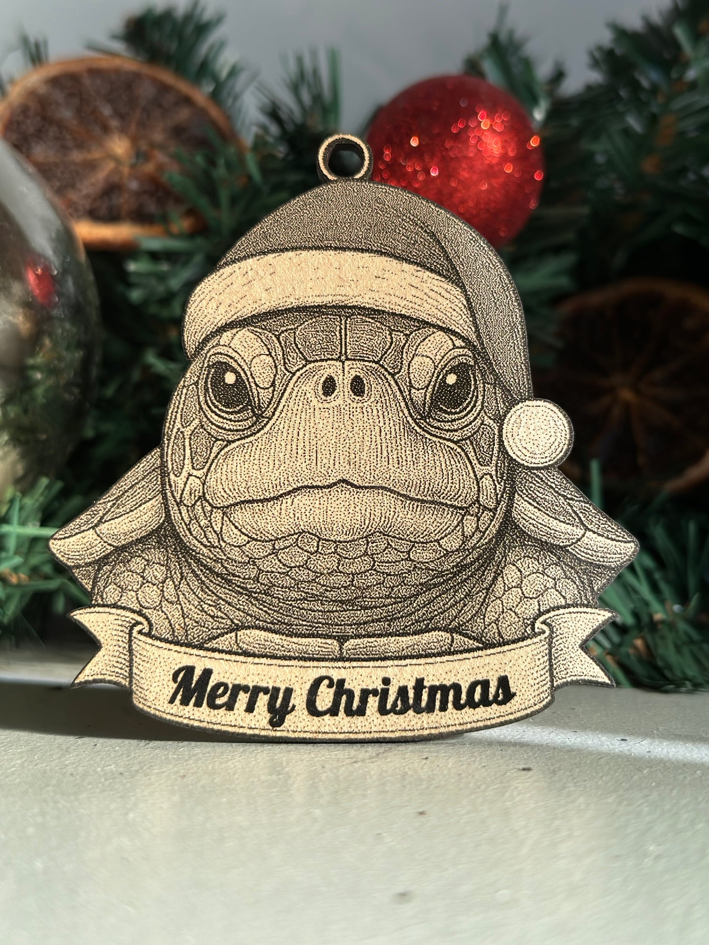 Decorative turtle ornament with 'Merry Christmas' banner on a Christmas tree.