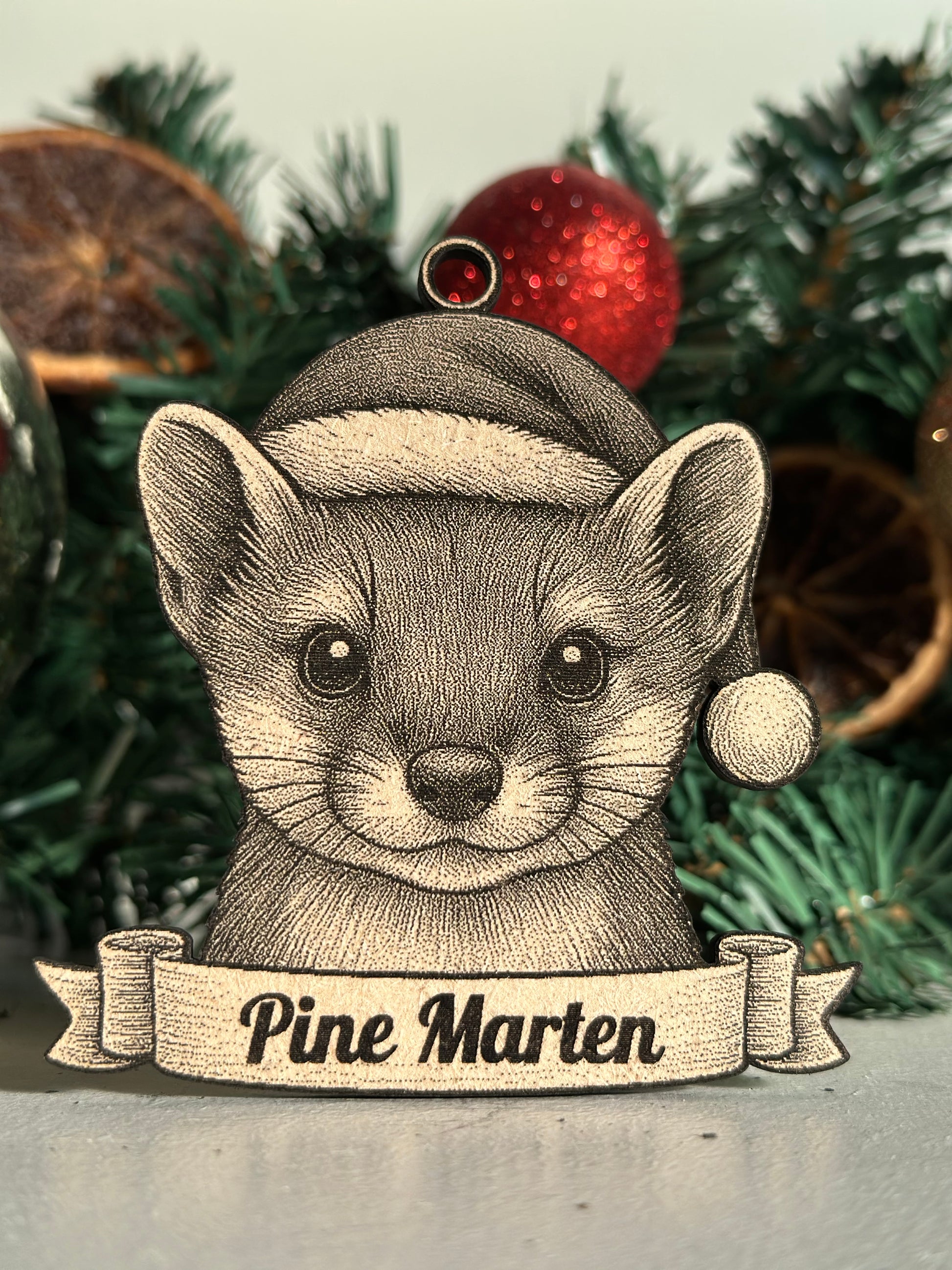 Decorative pine marten ornament on a Christmas tree with a red ornament.