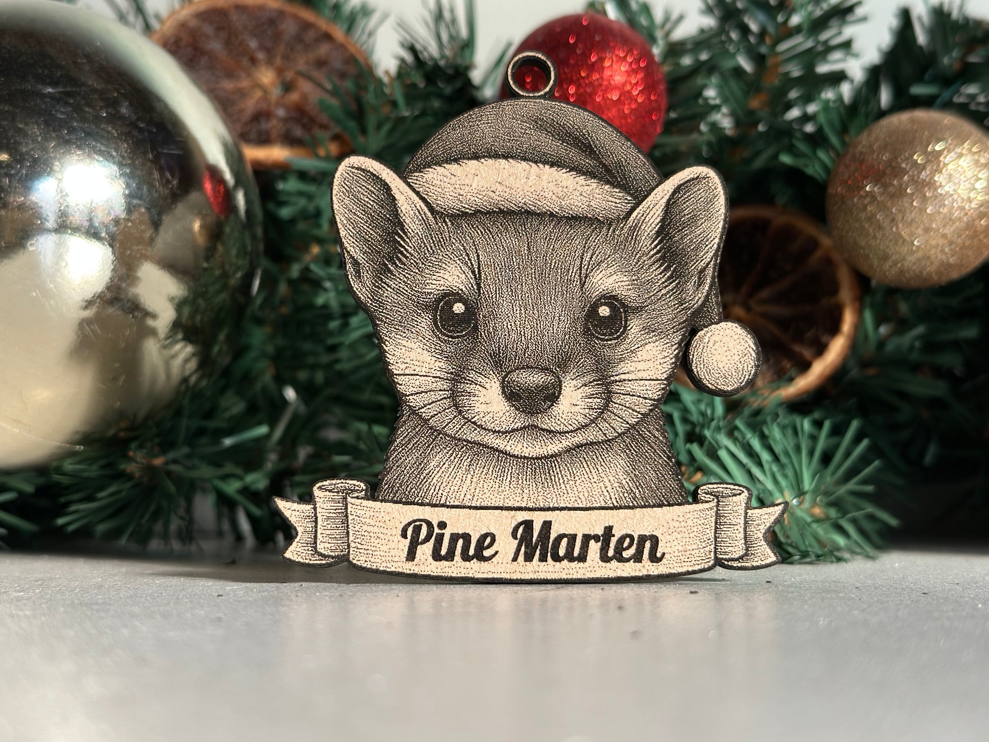 Decorative ornament of a Pine Marten with a banner on a Christmas tree.