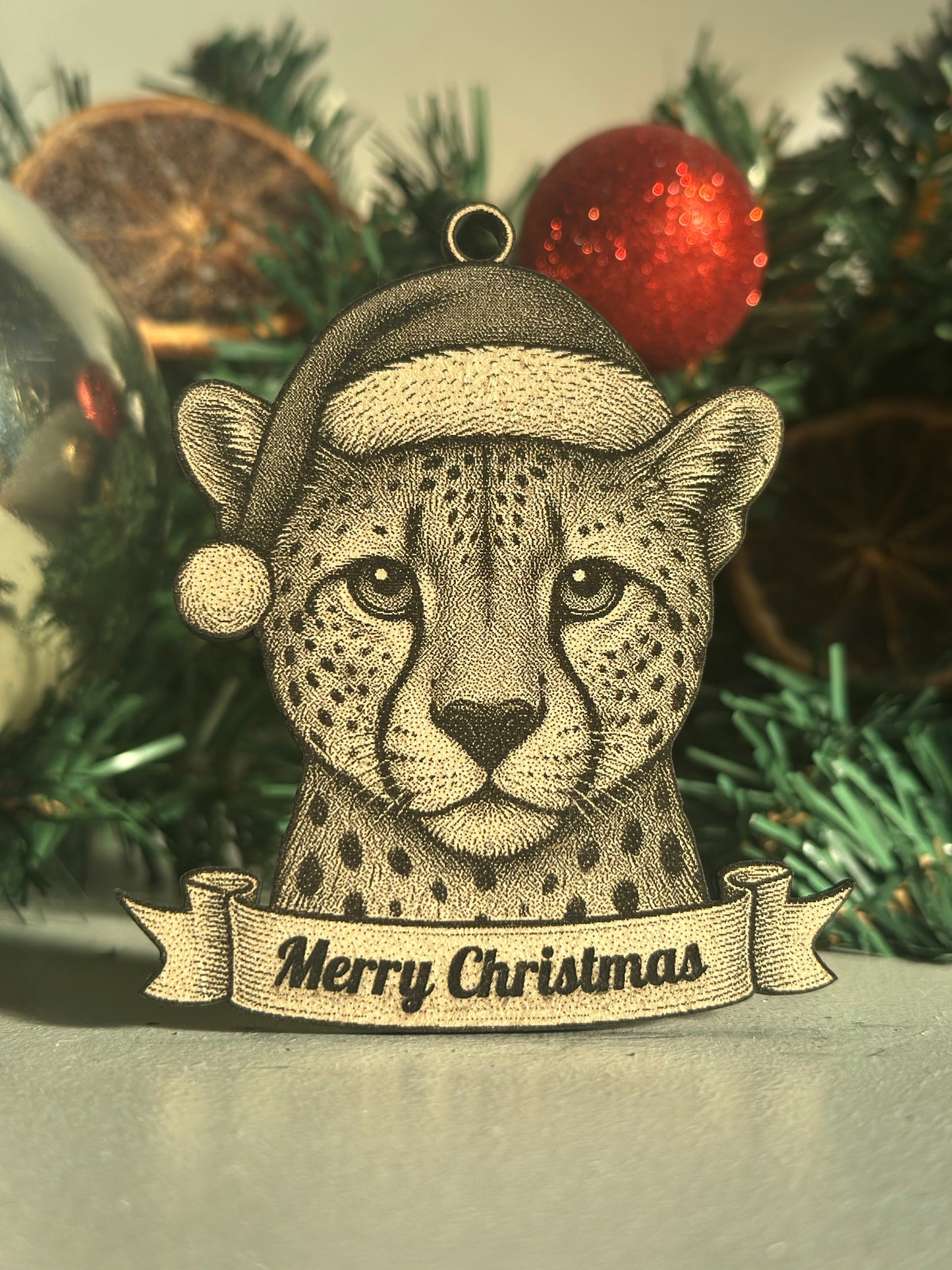 Decorative Christmas ornament with a cheetah wearing a Santa hat on a Christmas tree.